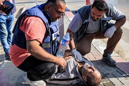 Un periodista y un paramédico ayudan a uno de los trabajadores palestinos después que se desplomara al llegar al cruce fronterizo de Rafah.