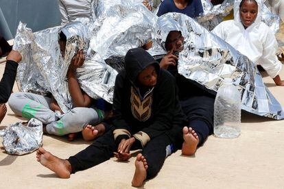 Migrantes esperan sentados en una base naval tras ser rescatados por los guardacostas libios, en Trípoli, Libia.