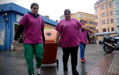 Las voluntarias empujan por las calles de A Coruña uno de los contenedores con los que recogen el aceite usado.