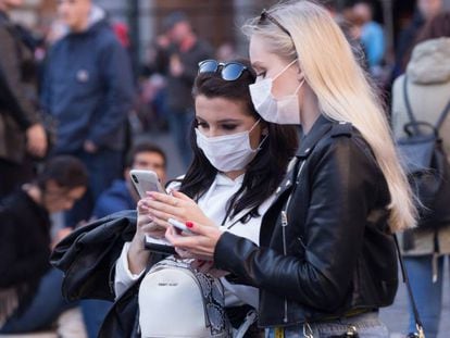 Dos mujeres consultan el móvil protegidas del coronavirus con mascarillas, en la plaza de la Rotonda (Roma). En vídeo, lo que se sabe del virus.