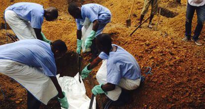 Cuatro voluntarios del personal sanitario entierran a una víctima del ébola en Sierra Leona.