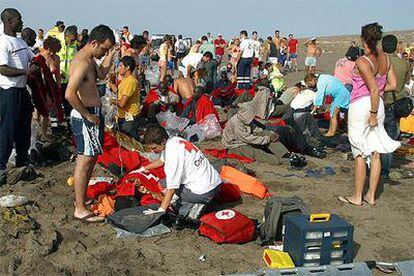 Los bañistas prestan los primeros auxilios en una playa de Gran Canaria a los extenuados subsaharianos llegados en un cayuco, el pasado 3 de agosto.