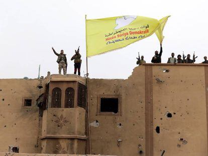 Combatientes de las Fuerzas Democráticas Sirias (FDS) ondean una bandera en Baguz,Siria. 