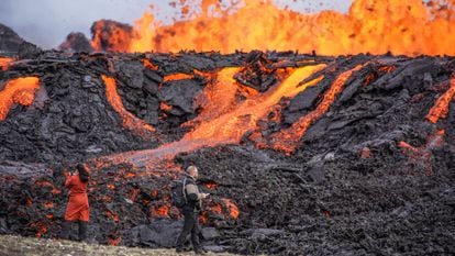 People look at the lava flowing on Fagradalsfjall volcano in Iceland on Wednesday Aug. 3, 2022, which is located 32 kilometers (20 miles) southwest of the capital of Reykjavik and close to the international Keflavik Airport. (AP Photo/Marco Di Marco)