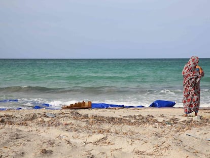 Un mujer permanece junto al mar en un punto de la playa donde quedan restos de barcas de madera y chalecos salvavidas en Sabrata, Libia.