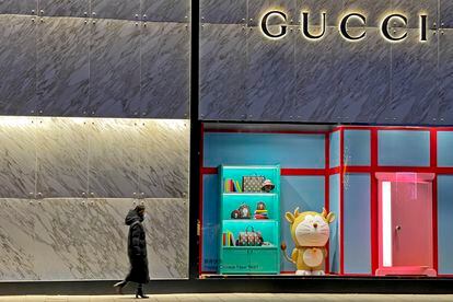 Una mujer pasea frente a una 'boutique' de Gucci en Pekín este mes de enero. Una figura de Doraemon decora el escaparate.