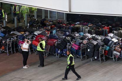 Trabajadores del aeropuerto de Heathrow en Londres junto a maletas apiladas en la terminal 2, el pasado 19 de junio.