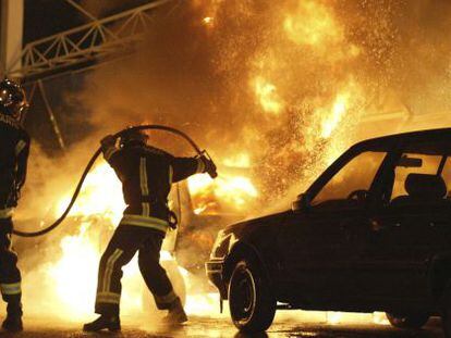 Foto de noviembre de 2005 que muestra a bomberos extinguiendo un incendio en un coche incendiado al sur de Par&iacute;s. 