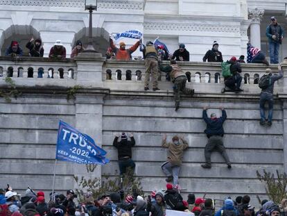 Los partidarios del presidente Donald Trump escalan el muro oeste del Capitolio de los Estados Unidos.