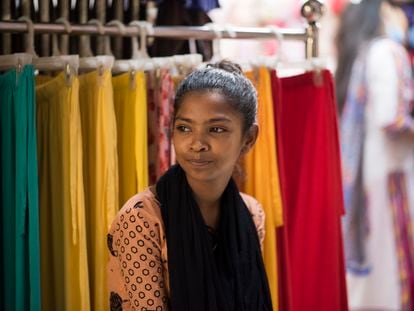 Sumaya, una niña de 14 años, frente a la tienda de ropa donde trabaja desde hace dos años, en Bangladés.