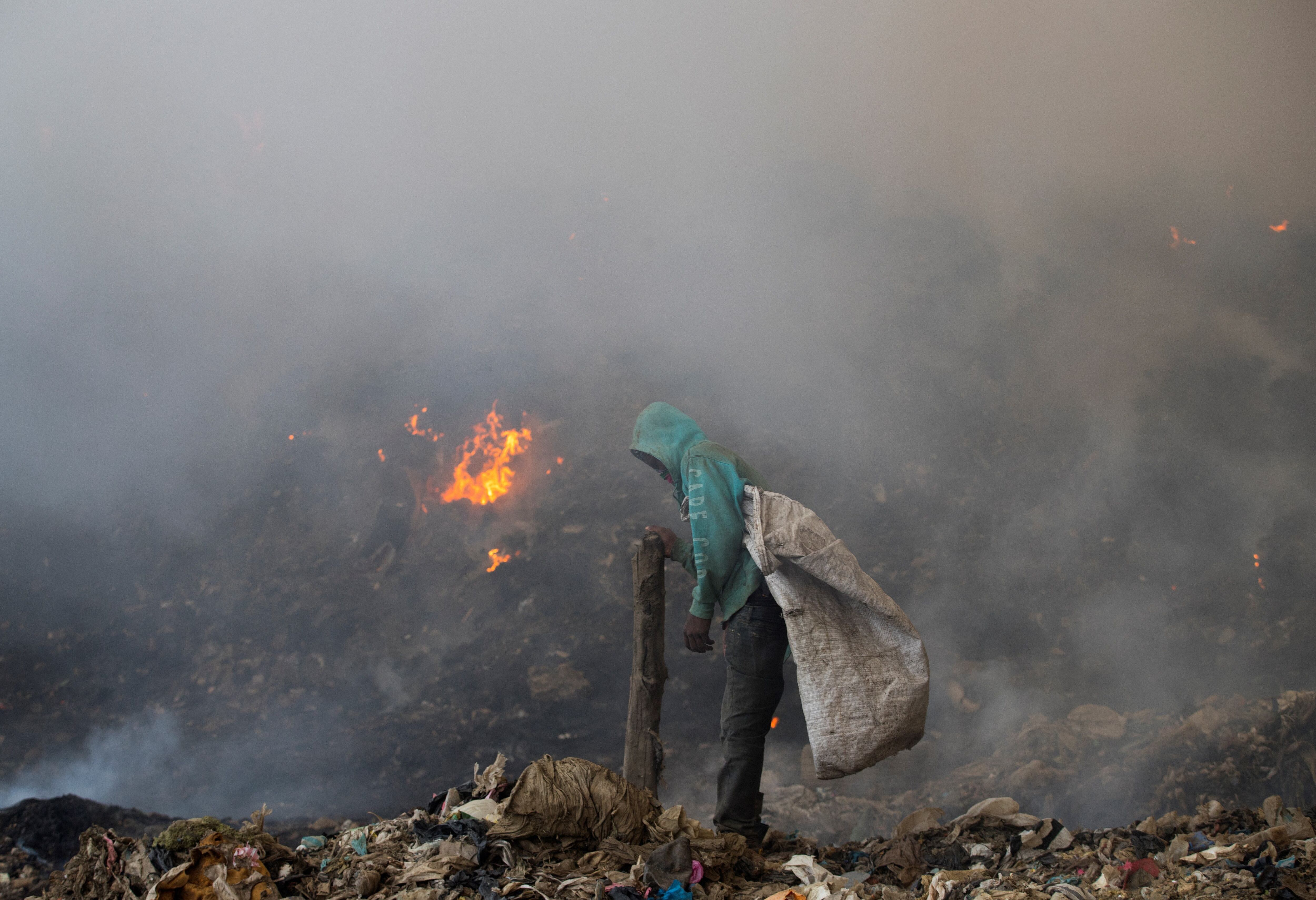 Un trabajador busca entre la basura para reciclar durante el gigantesco incendio en el vertedero de Duquesa, en abril de 2020.