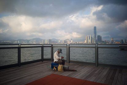 Un anciano empaca su equipo de pesca en una plataforma de observación en el puerto Victoria de Hong Kong.