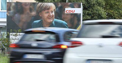 Varios coches pasan por delante de un cartel electoral de Angela Merkel, candidata a la reelecci&oacute;n como canciller alemana, en Berl&iacute;n.