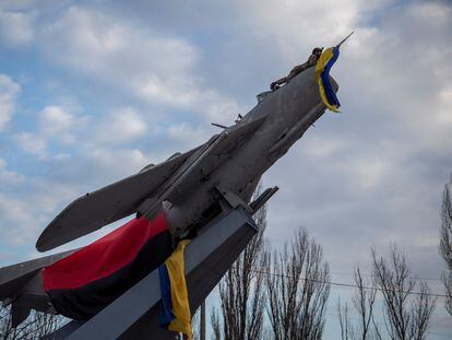 Un soldado ucranio coloca una bandera de su país sobre un caza fuera de servicio y reconvertido en monumento en Bajmut, en la región de Donetsk.