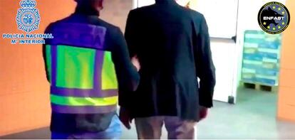 Un agente de la Policía Nacional conduce al fugitivo arrestado en Alicante por posesión ilícita de armas, explosivos y munición, en una toma de vídeo del ministerio del Interior.