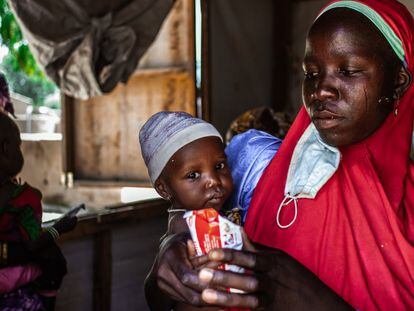 Una madre sostiene a su hijo, a quien está alimentando con un sobre de Plumpy Nut, una pasta de cacahuete alta en proteína.