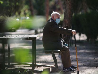 Un anciano con mascarilla descansa en el Parque Calero, en Madrid.