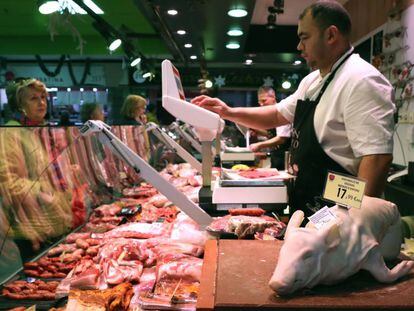 Un carnicero atiende a sus clientes en un mercado de Madrid.