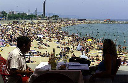 Una pareja come en la terraza de un restaurante del Puerto Olímpico de Barcelona.