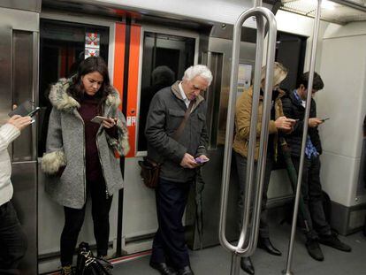 Viajeros del metro de Bilbao consultan sus móviles.