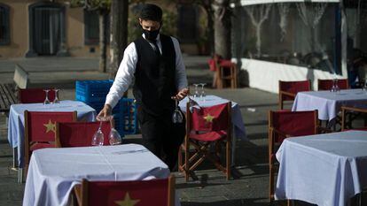 Un cambrer prepara les taules de la terrassa d'un restaurant de Barcelona, al gener.