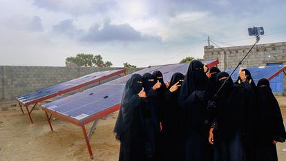 Iman Haddi y sus compañeras se toman una foto con el móvil delante de los paneles solares que han instalado.