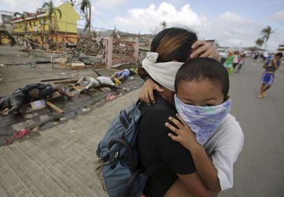 Una madre y su hijo se tapan la nariz al pasar junto a los cadáveres de varias víctimas del tifón Haiyan.