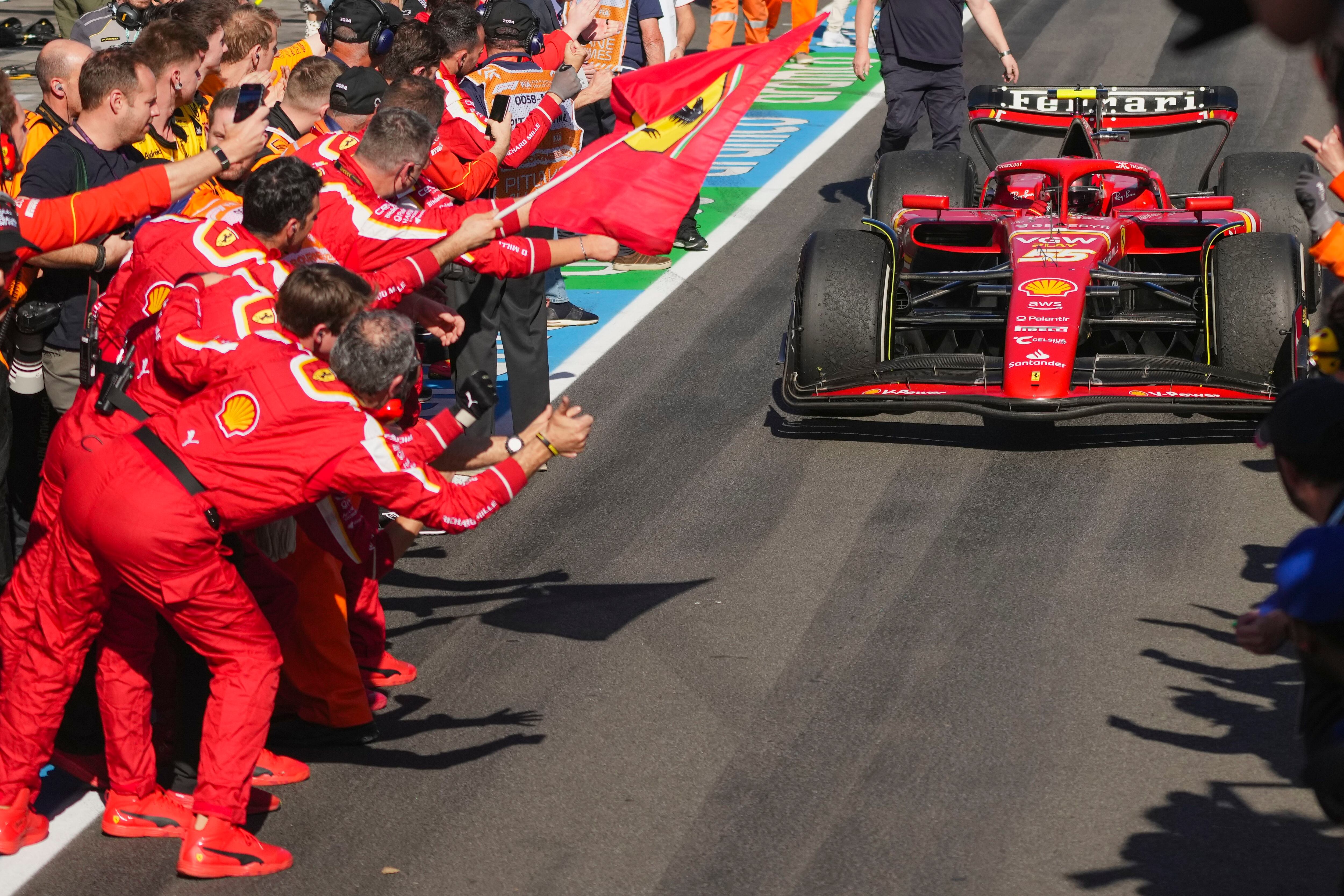 El piloto de Ferrari Carlos Sainz es recibido por su equipo tras cruzar la línea de meta este domingo en Melbourne. 