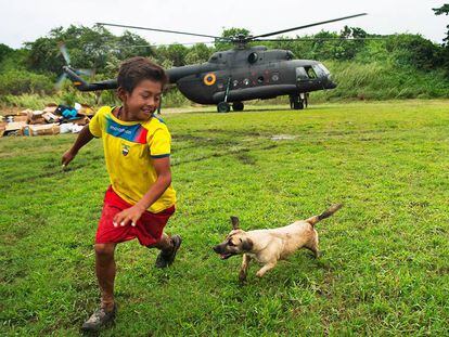 Luis Napa y su perro &quot;Pelusa&quot; juegan en el estadio de Pedernales, Ecuador, mientras un helic&oacute;ptero del Ej&eacute;rcito deja ayuda humanitaria.