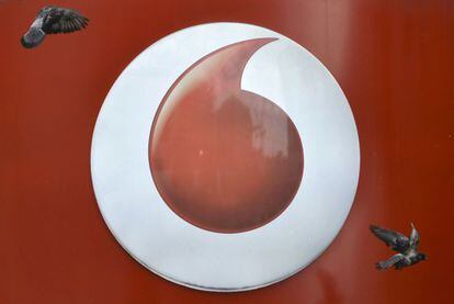 Dos palomas vuelan ante el logotipo de una tienda de Vodafone en Londres.