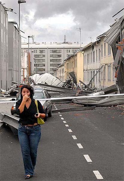 Una mujer camina por una calle de Caranza (Ferrol) llena de restos de tejados arrancados por el viento.