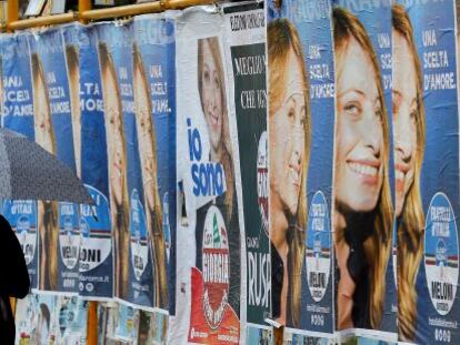 Una mujer pasa junto a varios carteles electorales en Roma (Italia). 