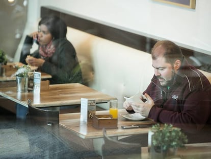 Dos personas desayunan enganchadas a sus dispositivos moviles
