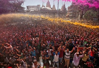Una multitud de devotos son rociados con agua de colores en las instalaciones del templo durante la celebración del Holi, el Festival de los colores, en Ahmedabad (India).