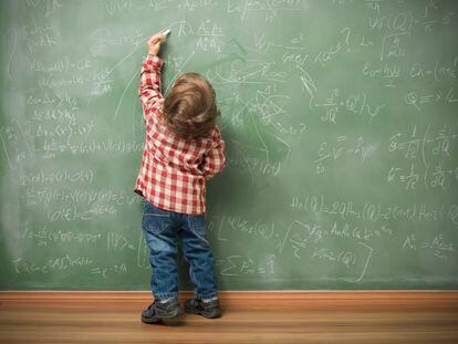 Un niño escribe con su mano izquierda en la pizarra.