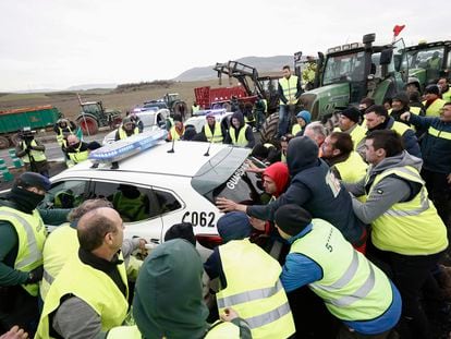 Varios agricultores mueven coches de la Guardia Civil para acceder a Pamplona este jueves.