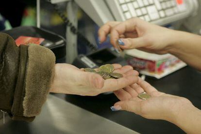 Una cajera ayuda a un cliente a contar monedas en un supermercado.