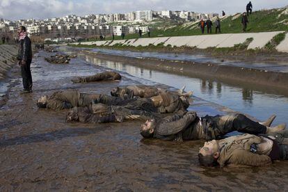 Alepo, Siria, 29 de enero de 2013. Un hombre permanece de pie junto a cadáveres de hombres ejecutados junto a un canal en Alepo, en el norte de Siria. Miembros del Ejército Libre de Siria (ELS) y activistas de la oposición al régimen han hallado 108 cadáveres amontonados en la orilla del río Quweiq, en Bustan al Qaser, barrio situado en el suroeste de Alepo, provincia del norte de Siria. Los cuerpos presentaban impactos de bala en la cabeza y las manos atadas a la espalda, signos de que podrían haber sido víctimas de una ejecución sumaria.