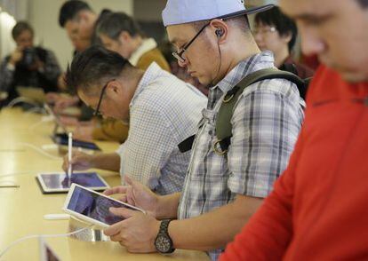 Clientes de una tienda de Apple probando sus tabletas iPad.