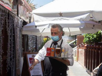 Un camarero lleva su pedido a unos clientes a una de las terrazas del Puerto Olímpico de Barcelona, este miércoles, cuando la ciudad entra en su tercer día en la fase 1 de la desescalada.