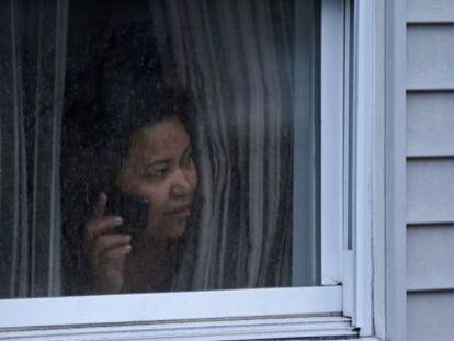 Una mujer mira por la ventana de su casa durante la busqueda policial