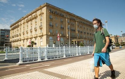 Un joven con mascarilla pasa por delante del hotel Maria Cristina, en San Sebastian.