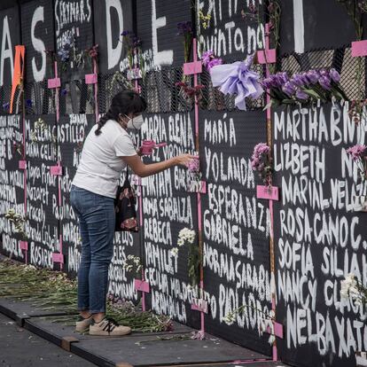 Una mujer pinta una cruz en la valla instalada en el Palacio Nacional en Ciudad de México, el día de hoy.