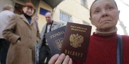 Una mujer muestra, frente a la oficina de migraci&oacute;n de Simfer&oacute;pol, su pasaporte ucranio y el ruso que acaba de recibir.