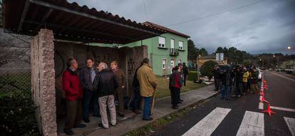 Vecinos de Tarago (Rianxo), observan desde la parada del bus la casa del detenido por la desaparici&oacute;n de Diana Quer.