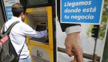 Un joven utiliza un cajero autom&aacute;tico de CaixaBank, en Madrid.