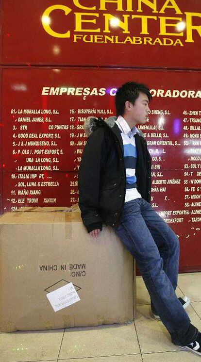Un comerciante chino descansa sobre una caja de mercancía en una nave del polígono de Cobo Calleja (Fuenlabrada).
