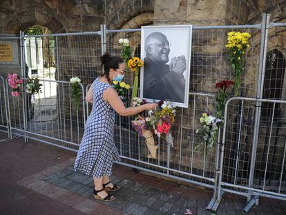 Una mujer coloca flores junto a un retrato de Desmond Tutu en la catedral de San Jorge de Ciudad del Cabo (Sudáfrica)