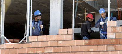 Tres obreros trabajan en la construcci&oacute;n de una vivienda. 