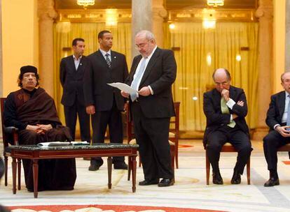 Gaddafi escucha sentado a Javier Gómez Navarro, en presencia de los empresarios Antonio Brufau y Luis del Rivero, a la derecha.